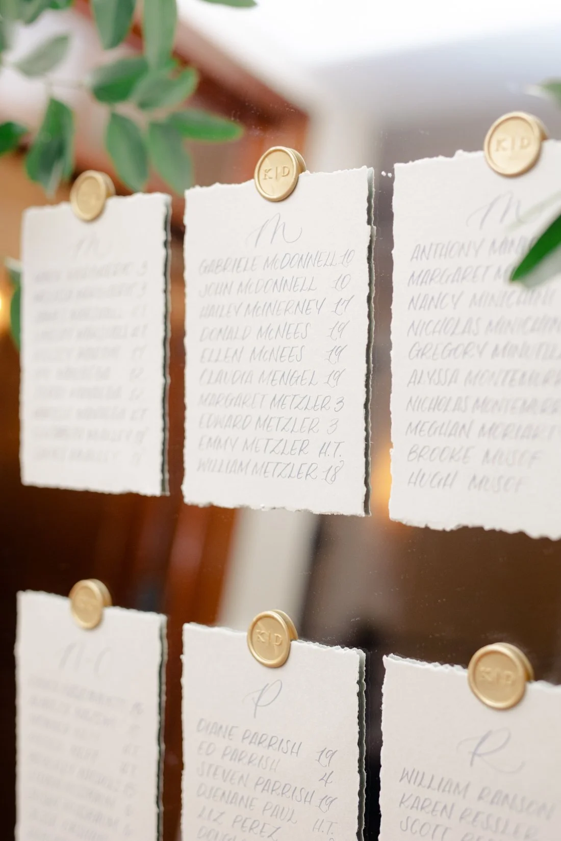 Escort card display with handwritten calligraphy and wax seals for wedding guests