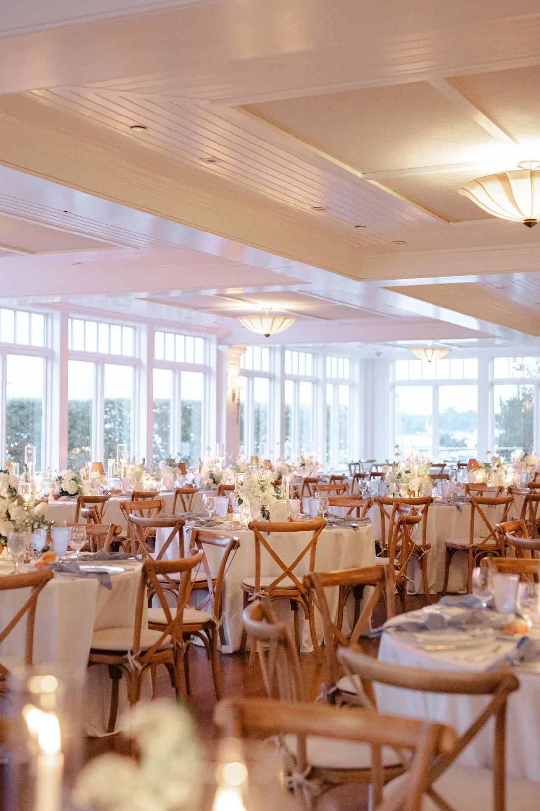 Wide view of reception room with wooden chairs and elegant table settings at Peconic Bay Yacht Club