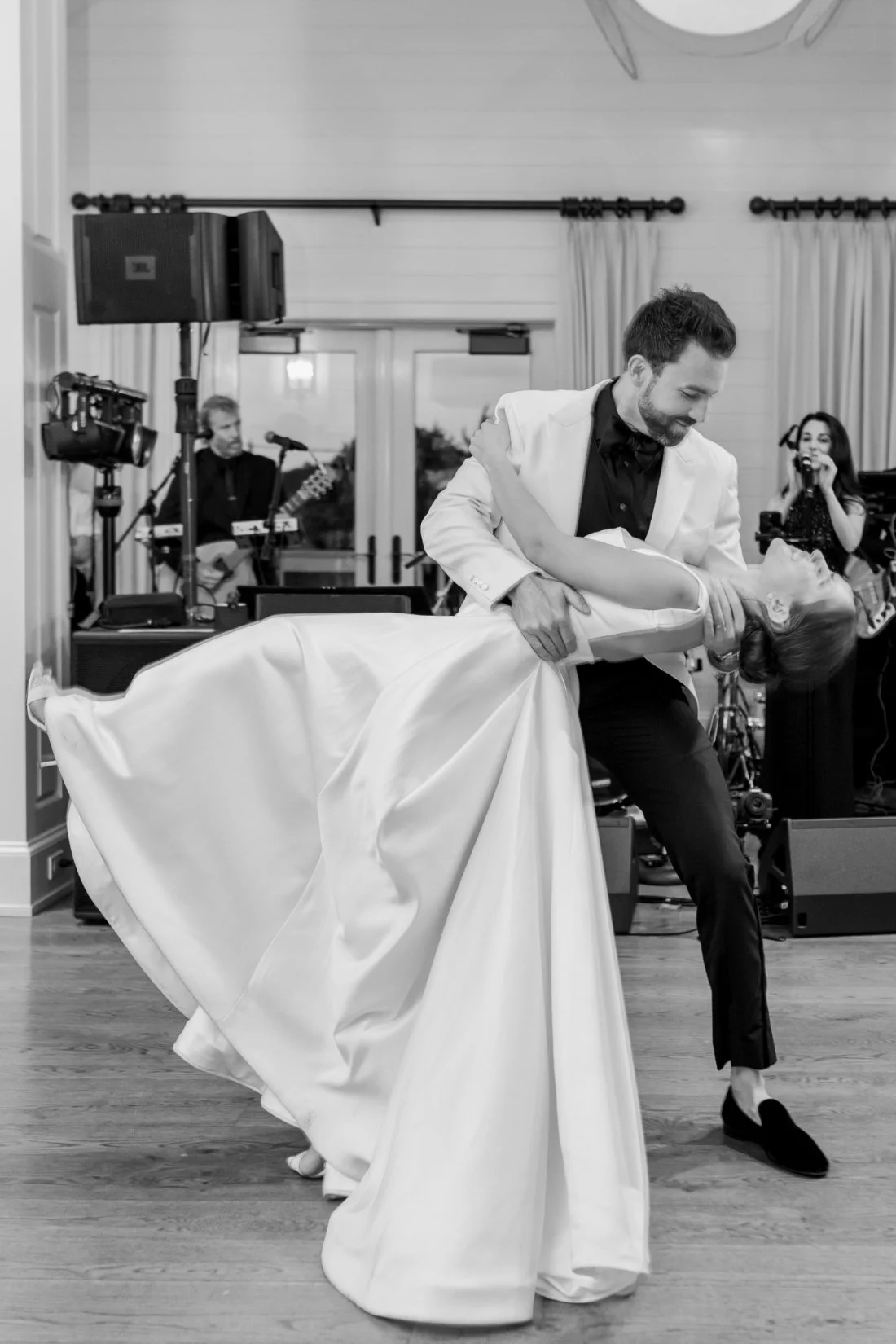 Black and white photo of bride and groom dancing during reception with live band