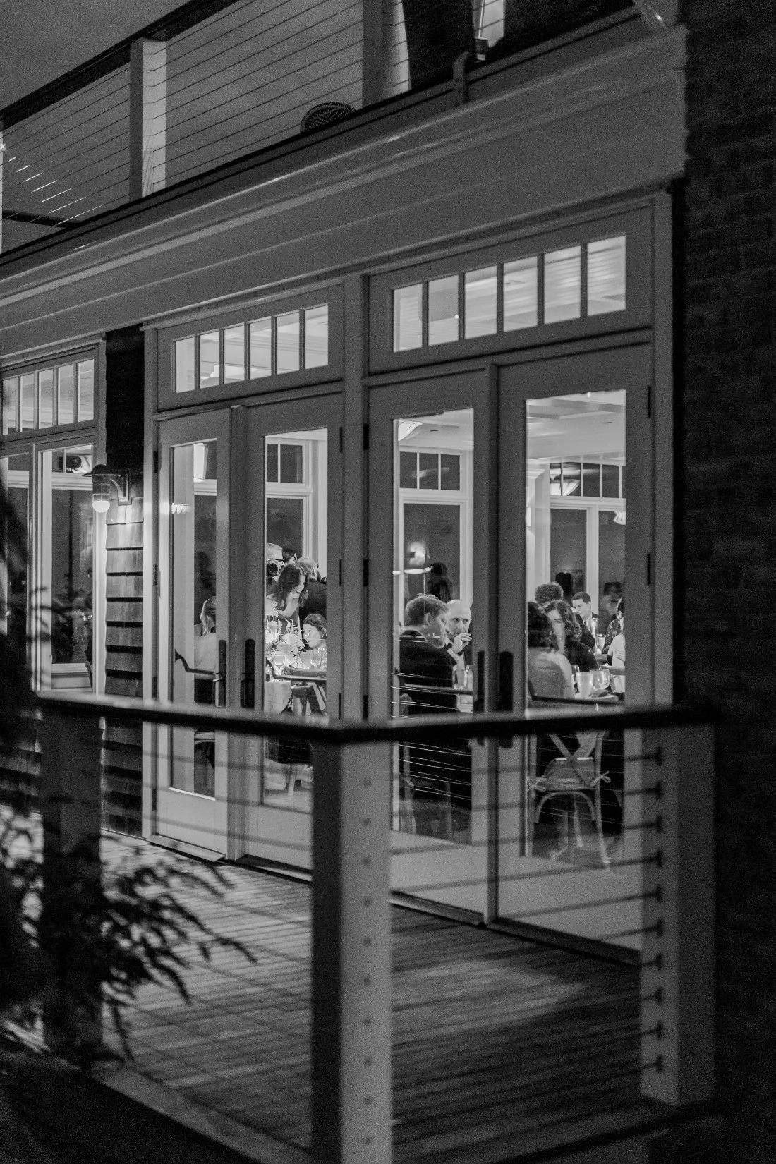 Exterior evening view of Peconic Bay Yacht Club with guests dining inside