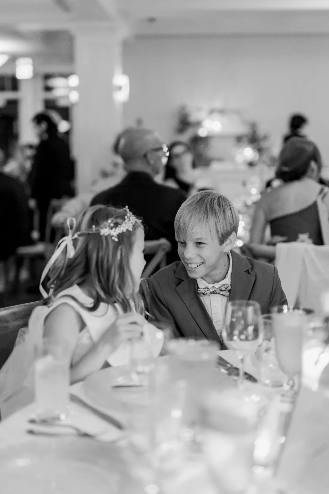 Black and white candid of kids laughing together at wedding reception table