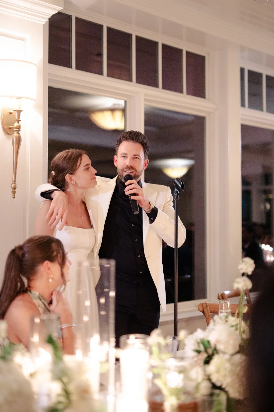 Groom speaking with arm around bride during reception at Peconic Bay Yacht Club