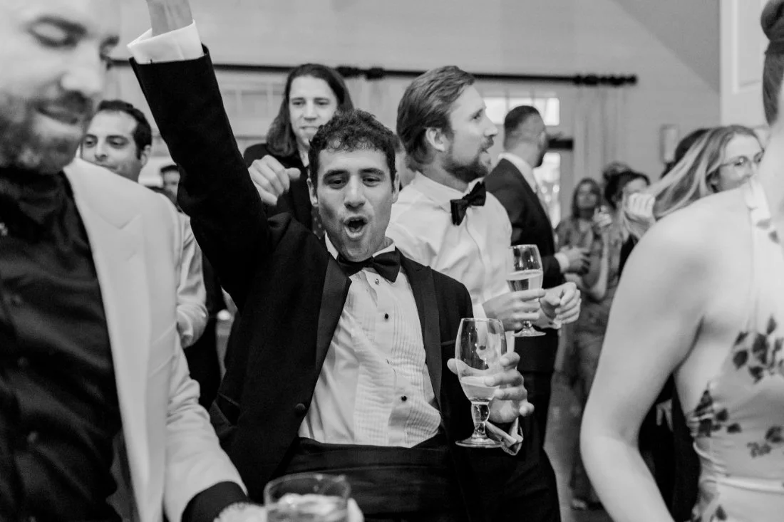 Groom dancing with groomsmen holding drinks at Peconic Bay Yacht Club wedding