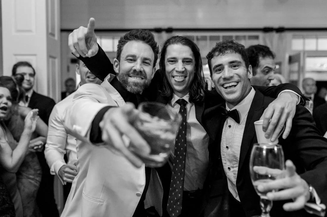 Groomsmen holding drinks and celebrating on the dance floor at Peconic Bay Yacht Club