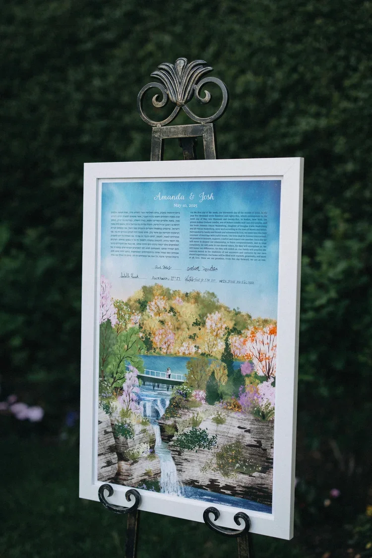 Custom welcome sign with artwork displayed on an easel at outdoor wedding ceremony entrance