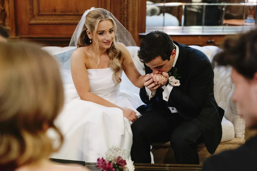 Groom kissing bride’s hand during emotional moment on wedding day