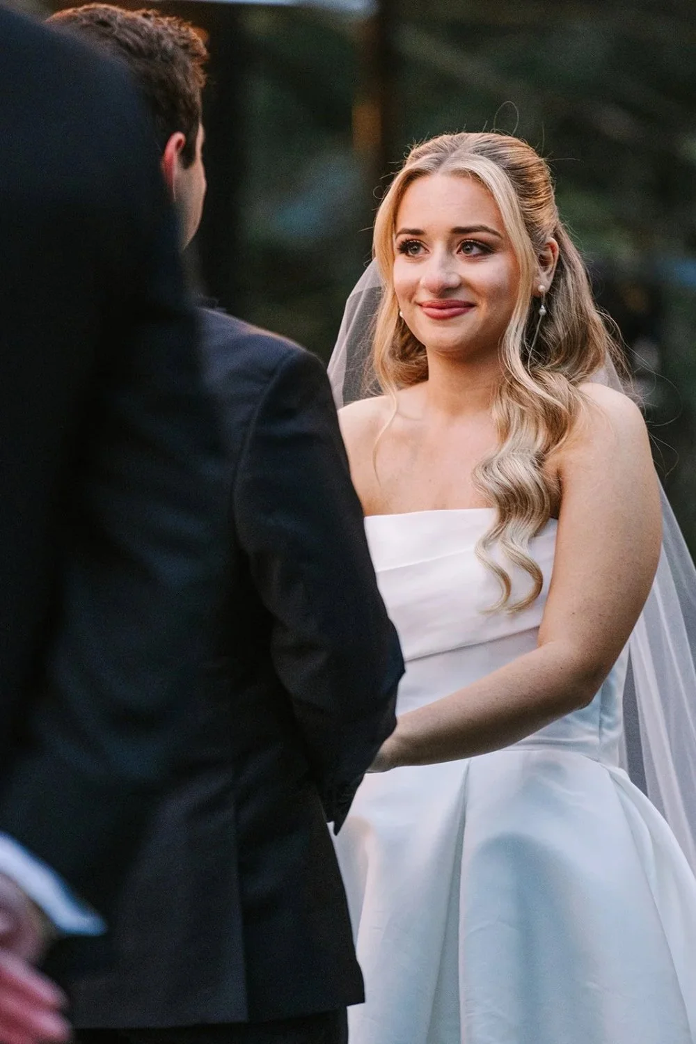Bride smiling during ceremony as she faces groom outdoors