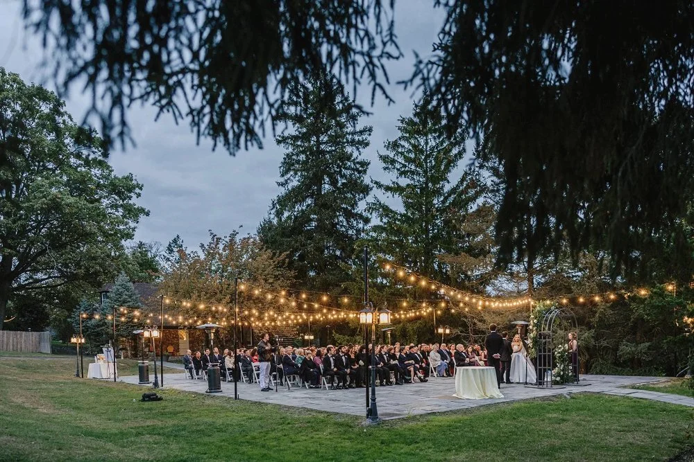 Guests seated under string lights during evening outdoor wedding ceremony