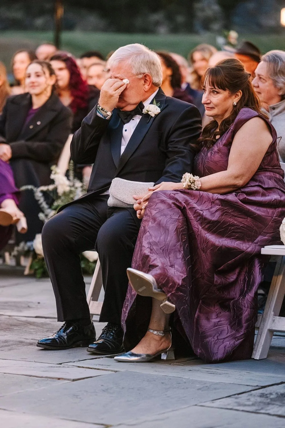 Parents reacting emotionally during ceremony with visible tears