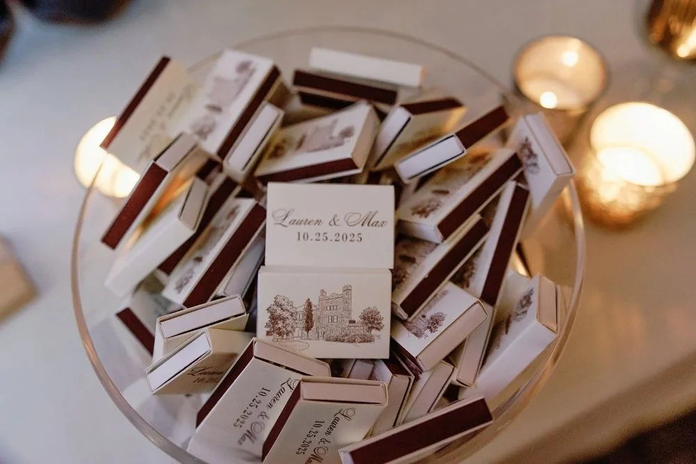 Custom matchbox wedding favors displayed in glass bowl with candles glowing behind