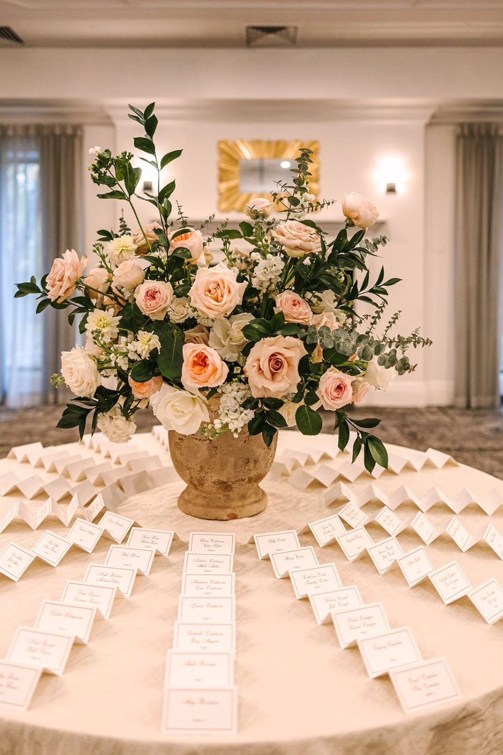 Escort card display with blush and ivory floral arrangement in elegant reception space