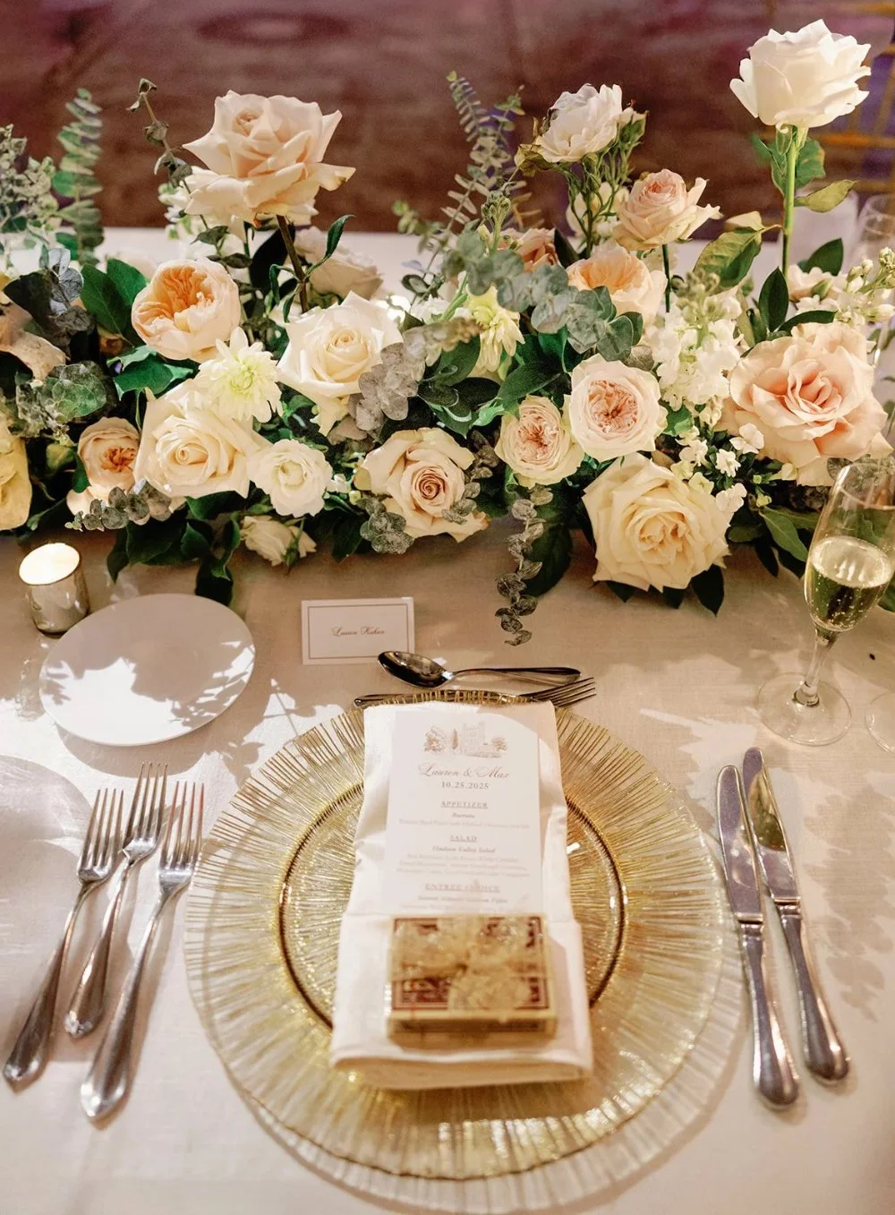 Romantic head table design with gold charger plates and abundant floral centerpiece