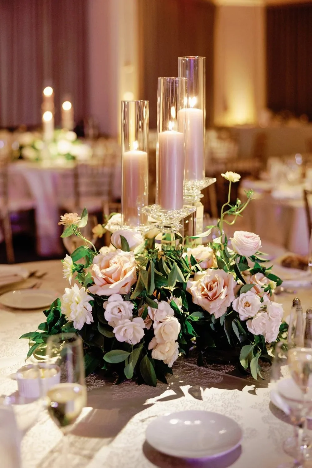 Elevated candle centerpiece surrounded by soft blush and ivory florals