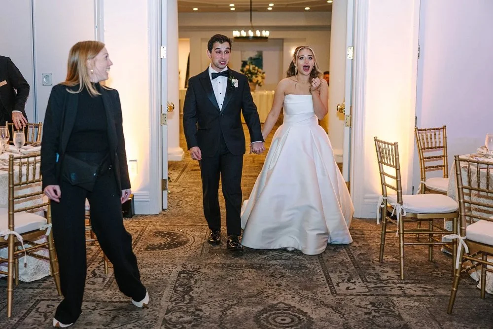 Bride and groom making their grand entrance into reception with planner guiding them