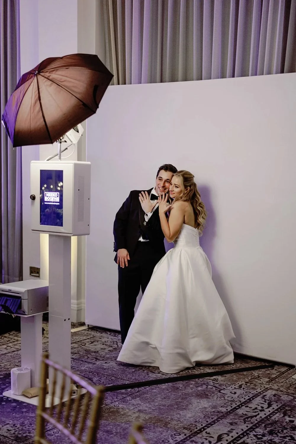 Newlyweds posing in photo booth with fun and playful expressions