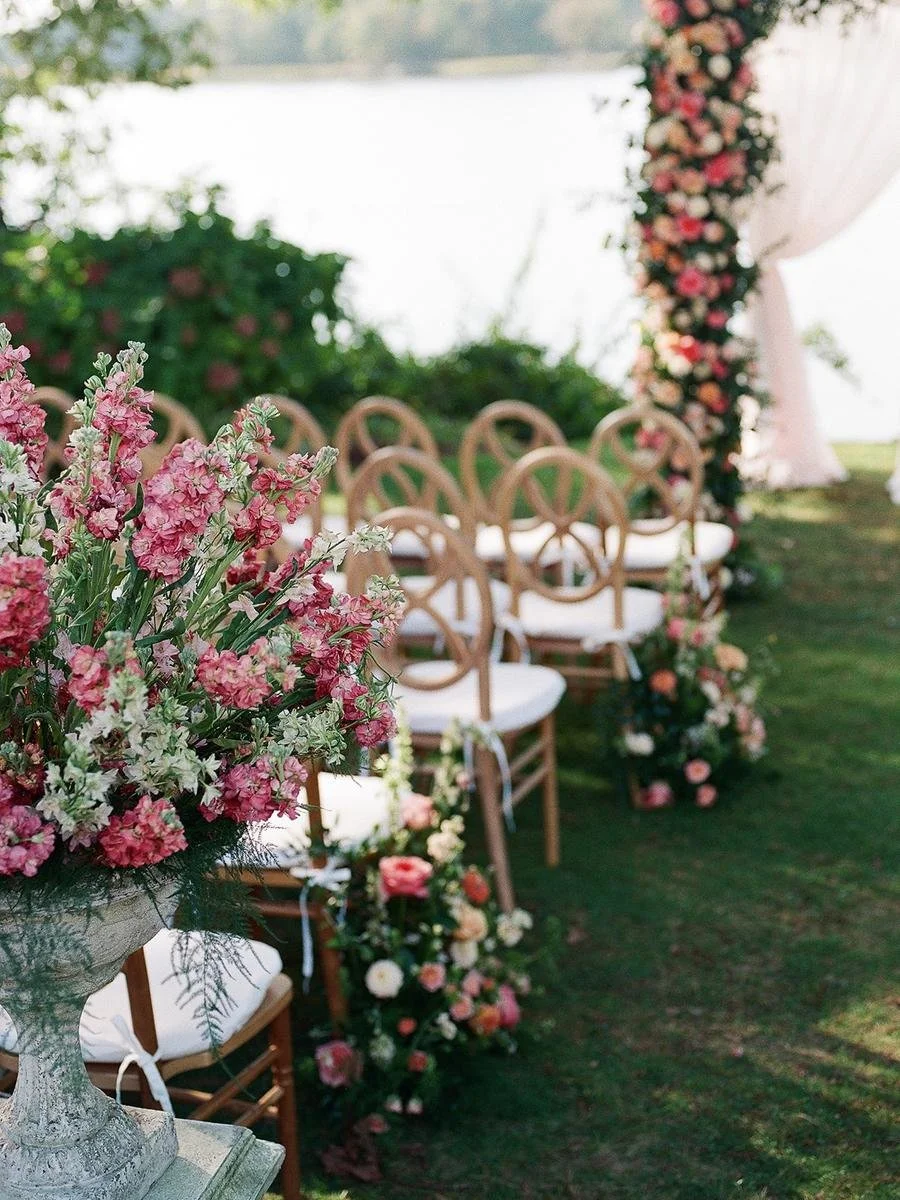 Floral aisle arrangements and wooden ceremony chairs set the scene for a romantic Wainwright House wedding ceremony.