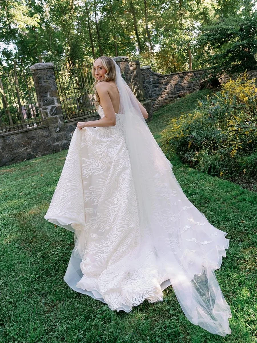 Bride walks through the gardens in a textured ballgown and cathedral veil at Wainwright House.