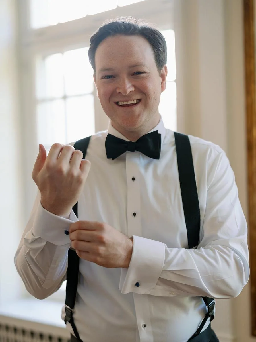 Groom adjusts his cufflinks while getting ready for a Wainwright House wedding in Rye, New York.