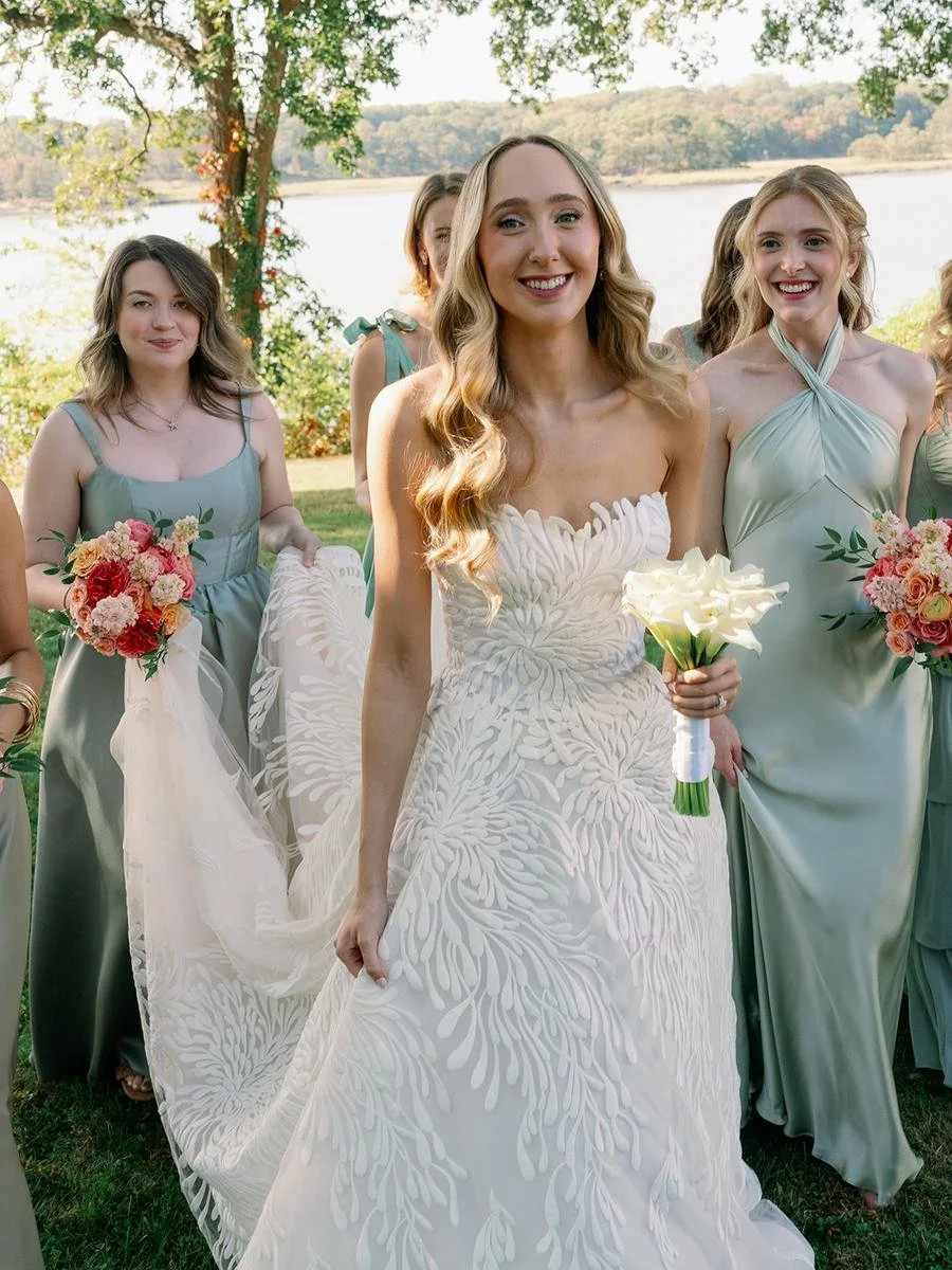 Bride carrying a white calla lily bouquet walks with bridesmaids during a Wainwright House wedding.