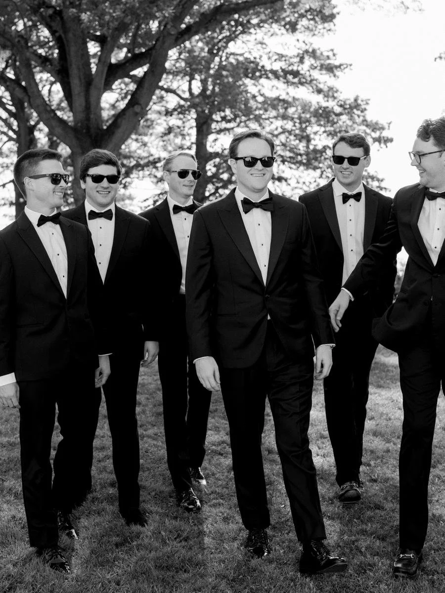 Groom and groomsmen in black tuxedos gather for portraits ahead of a waterfront Wainwright House wedding.