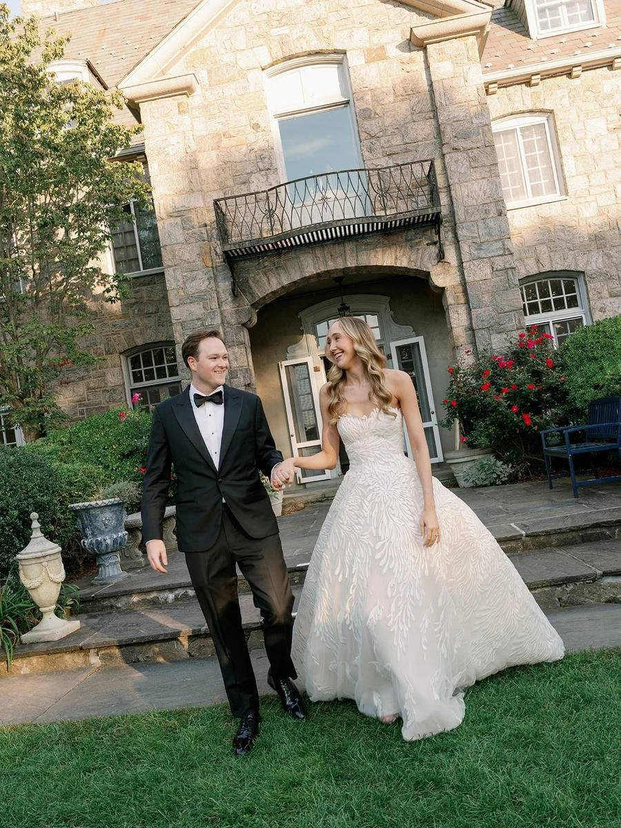 Newlyweds walk hand in hand in front of the historic mansion during their Wainwright House wedding celebration.