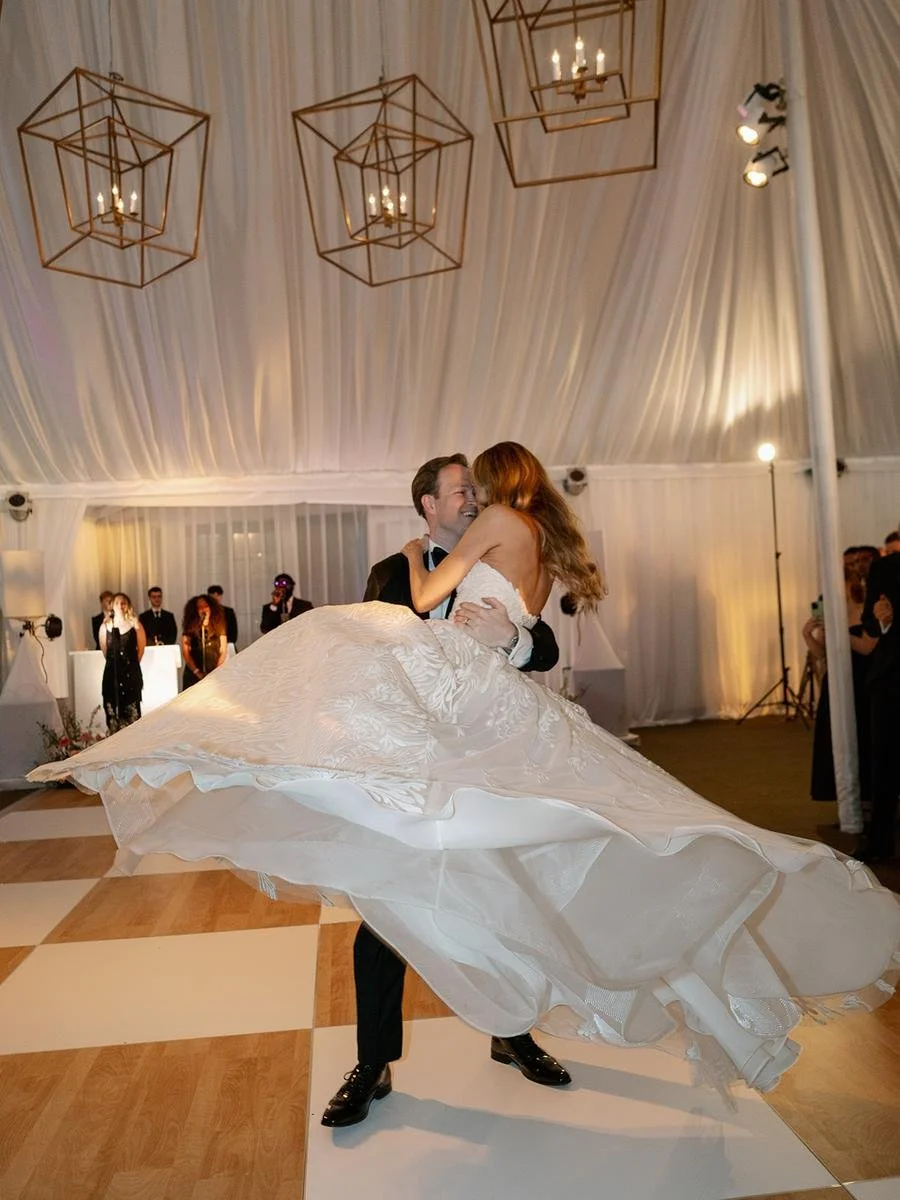 Groom twirling the bride across the dance floor during their first dance at a Wainwright House wedding.