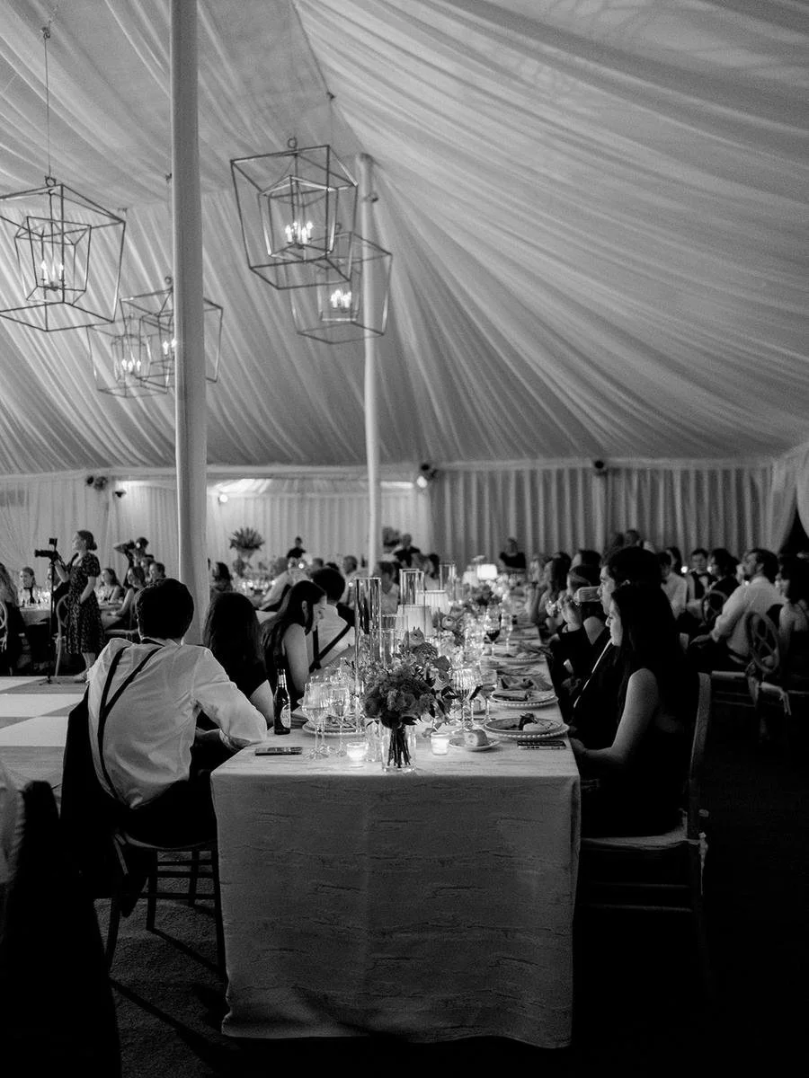 Guests seated at candlelit reception tables beneath a draped tent during a Wainwright House wedding celebration.