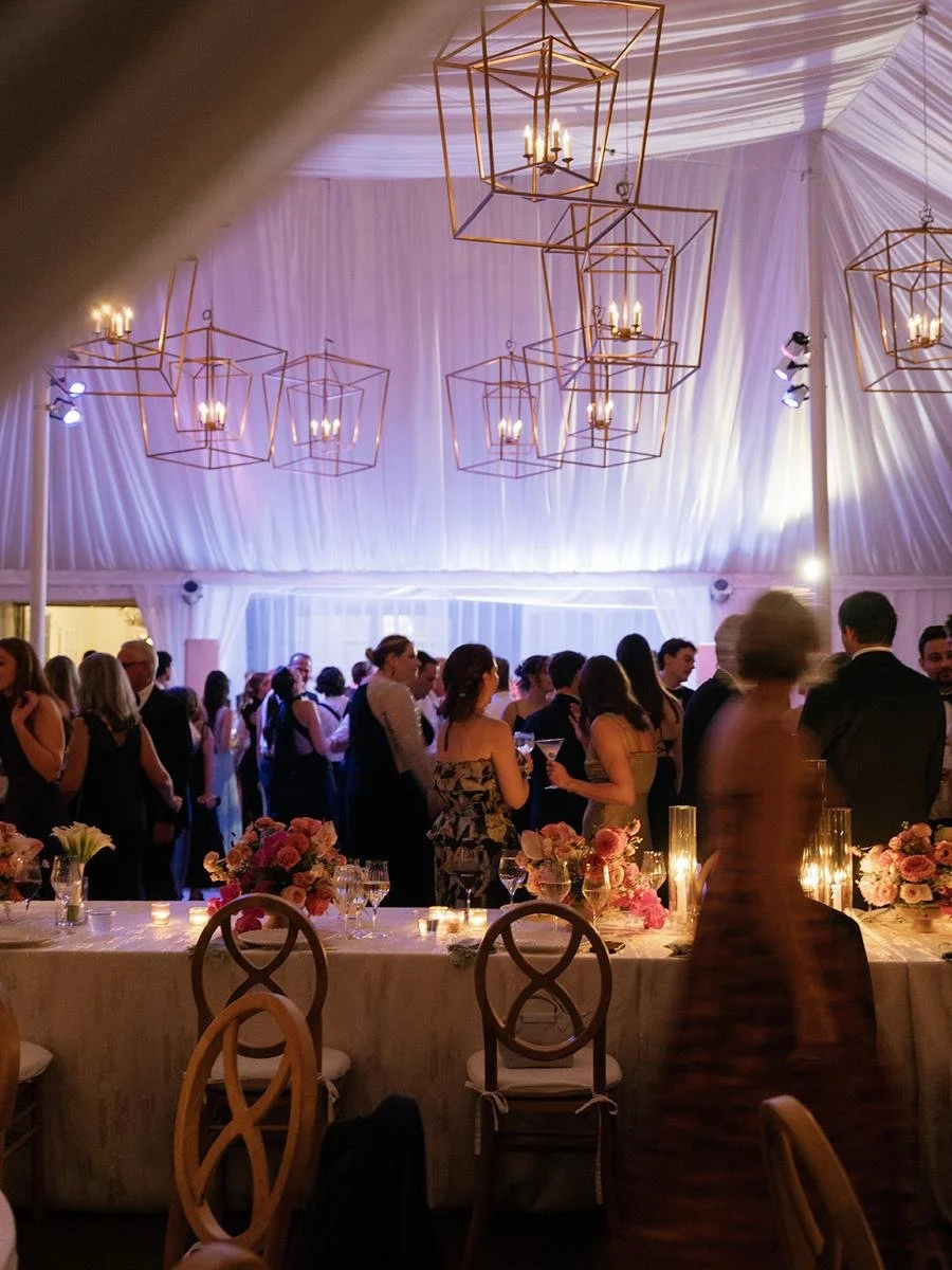 Wedding guests dancing and celebrating beneath glowing chandeliers at a Wainwright House wedding reception.