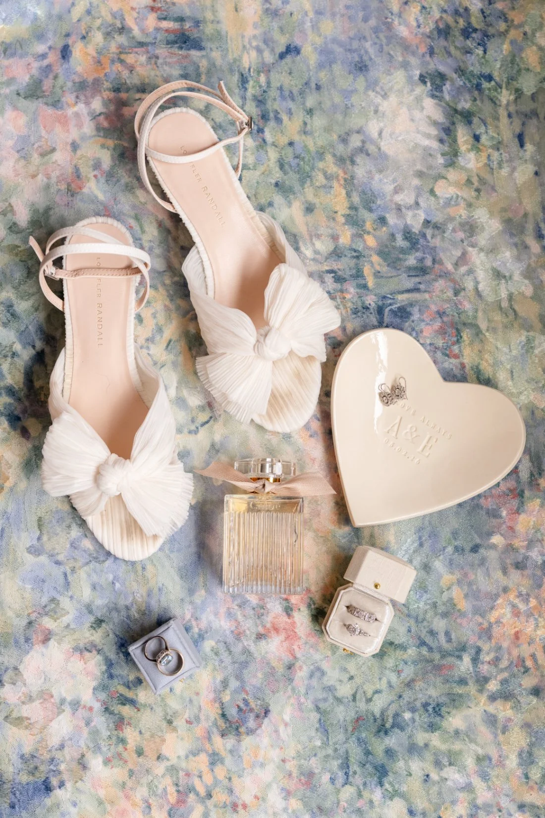 Bridal shoes, perfume, jewelry, and wedding rings arranged with Quaker Ridge Golf Club wedding details
