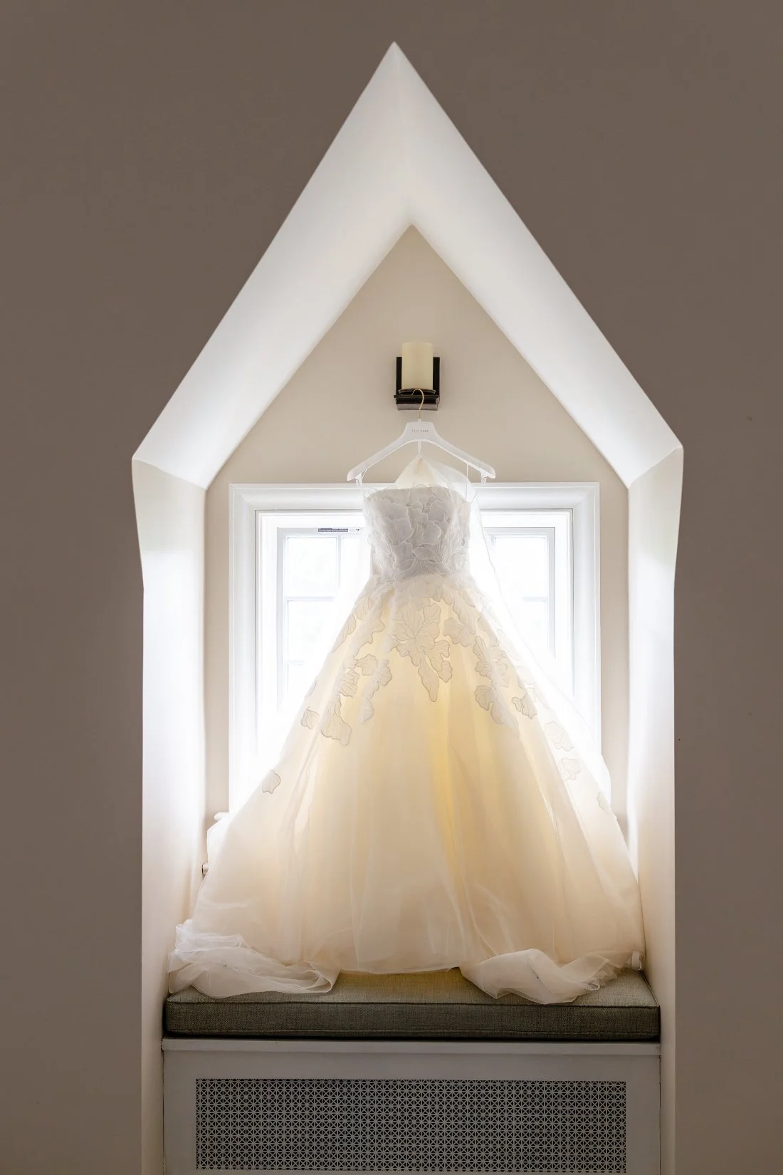 Strapless floral appliqué wedding gown hanging before a spring New York wedding