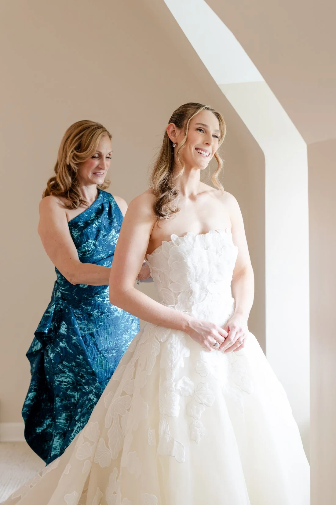 Bride getting into her floral appliqué gown for her Quaker Ridge Golf Club wedding