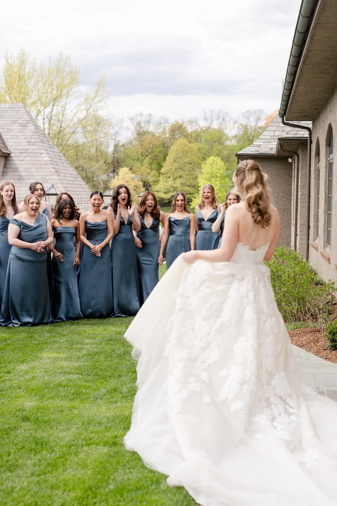 Bridesmaids in dusty blue dresses reacting to the bride at her Quaker Ridge Golf Club wedding