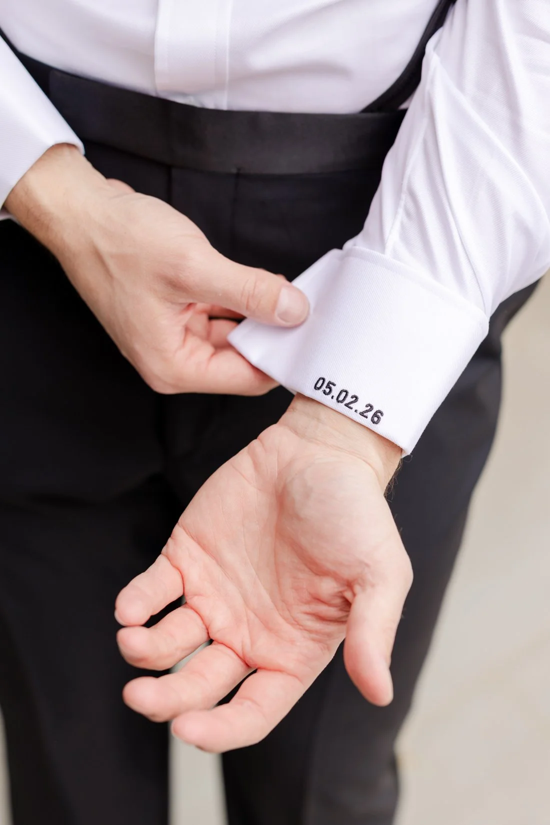 Close-up of the groom’s custom embroidered wedding shirt cuff featuring the wedding date during wedding preparations at Quaker Ridge Golf Club.