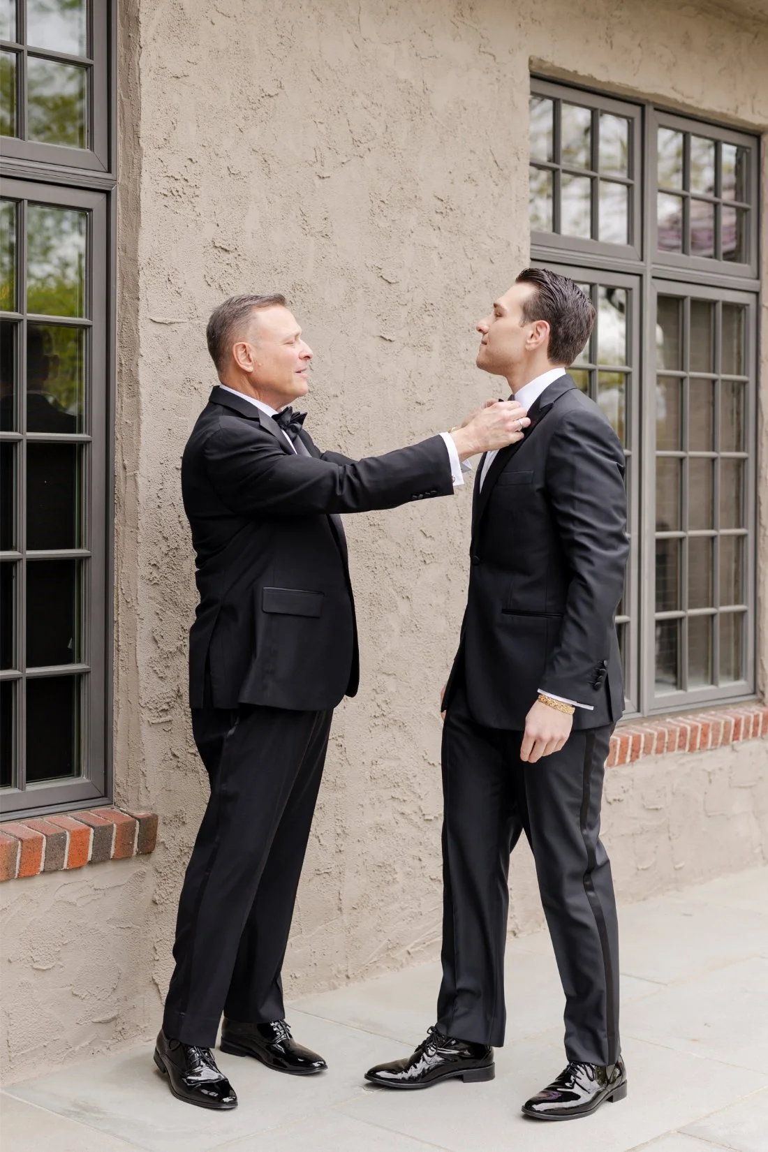 Groom receiving help adjusting his tuxedo before the wedding ceremony at Quaker Ridge Golf Club in New York.