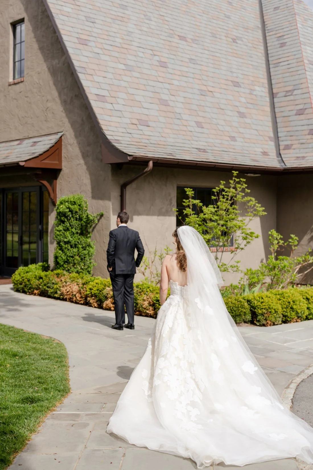 Bride approaches groom from behind for their first look at a Quaker Ridge Golf Club wedding