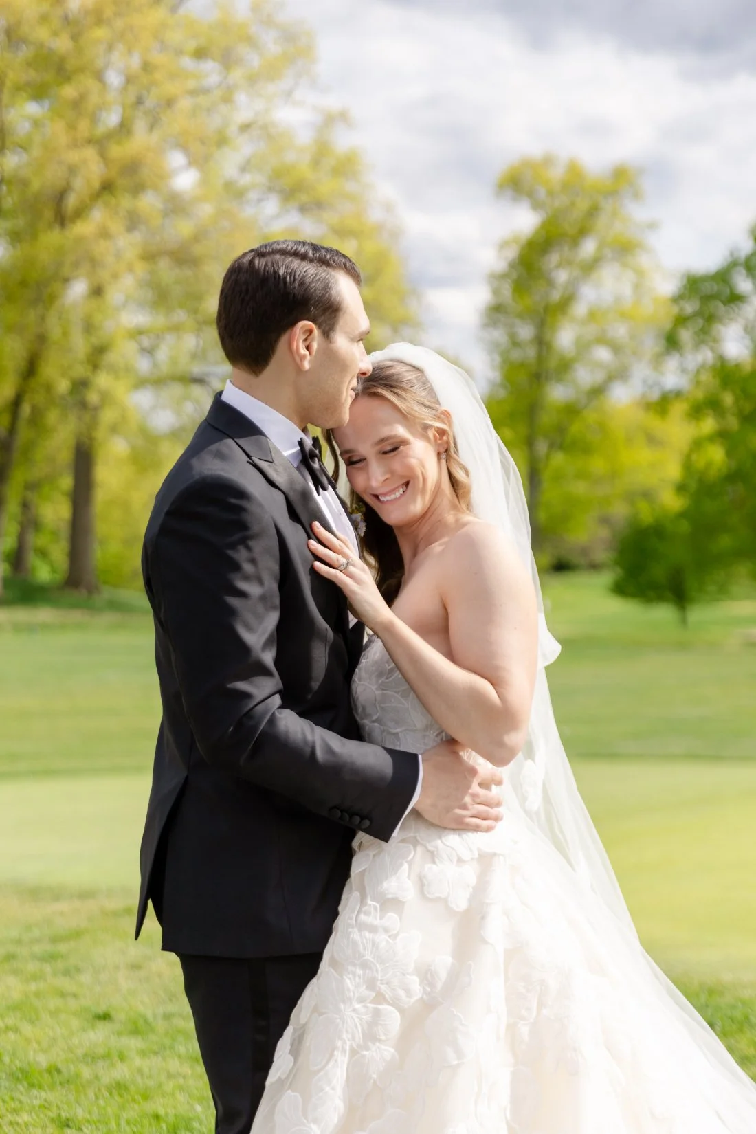 Groom kisses bride’s forehead during romantic outdoor wedding portraits