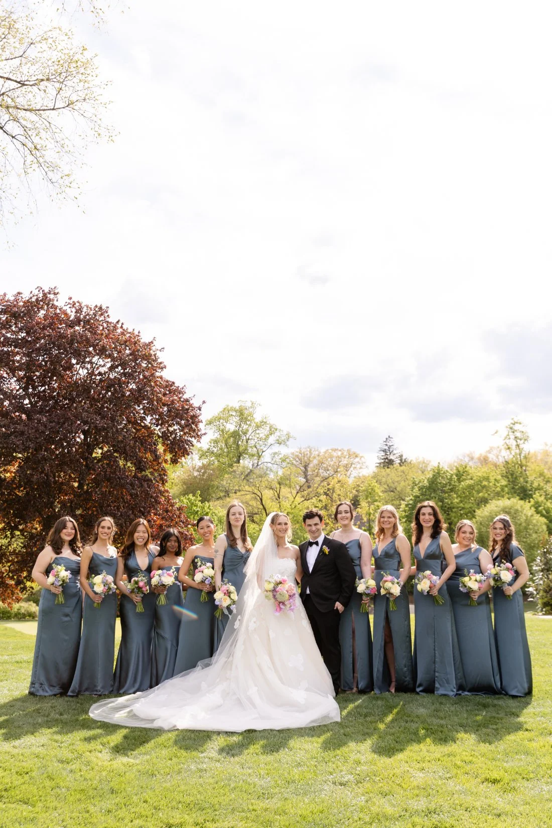 Bride and groom pose with bridesmaids in blue dresses at their Quaker Ridge Golf Club wedding