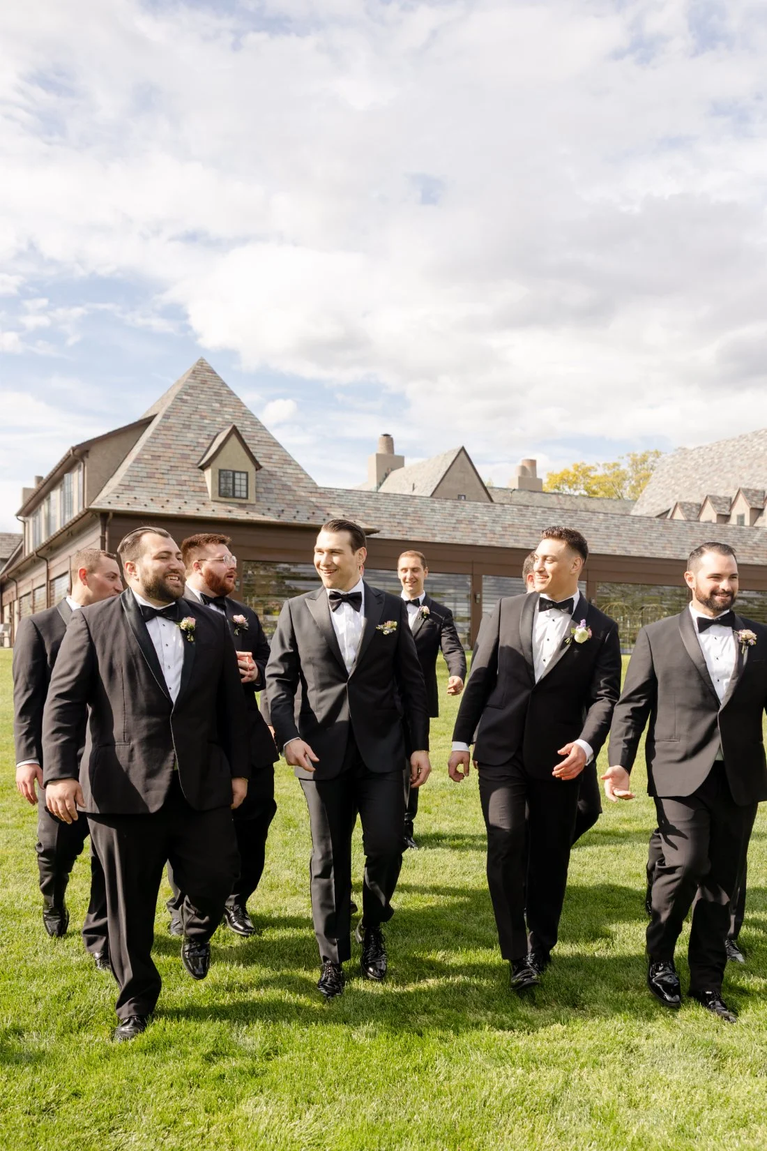 Groom walks with groomsmen in black tuxedos during a Quaker Ridge Golf Club wedding