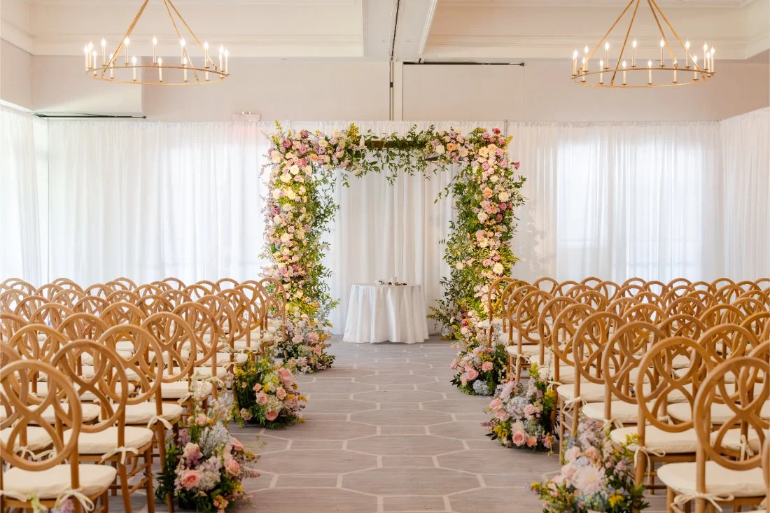 Floral chuppah and colorful aisle flowers set for a Quaker Ridge Golf Club wedding ceremony.