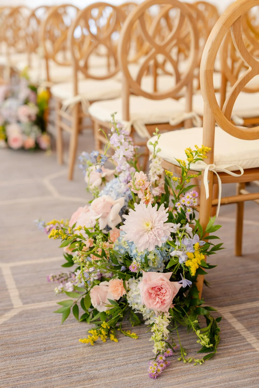 Colorful floral ceremony decor lining the aisle at a Quaker Ridge Golf Club wedding.