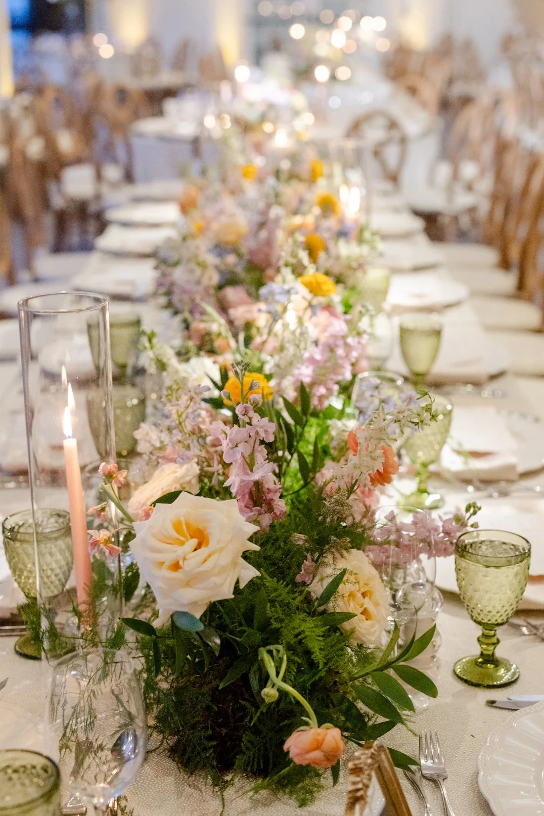 Long reception table decorated with flowers for a Quaker Ridge Golf Club wedding.