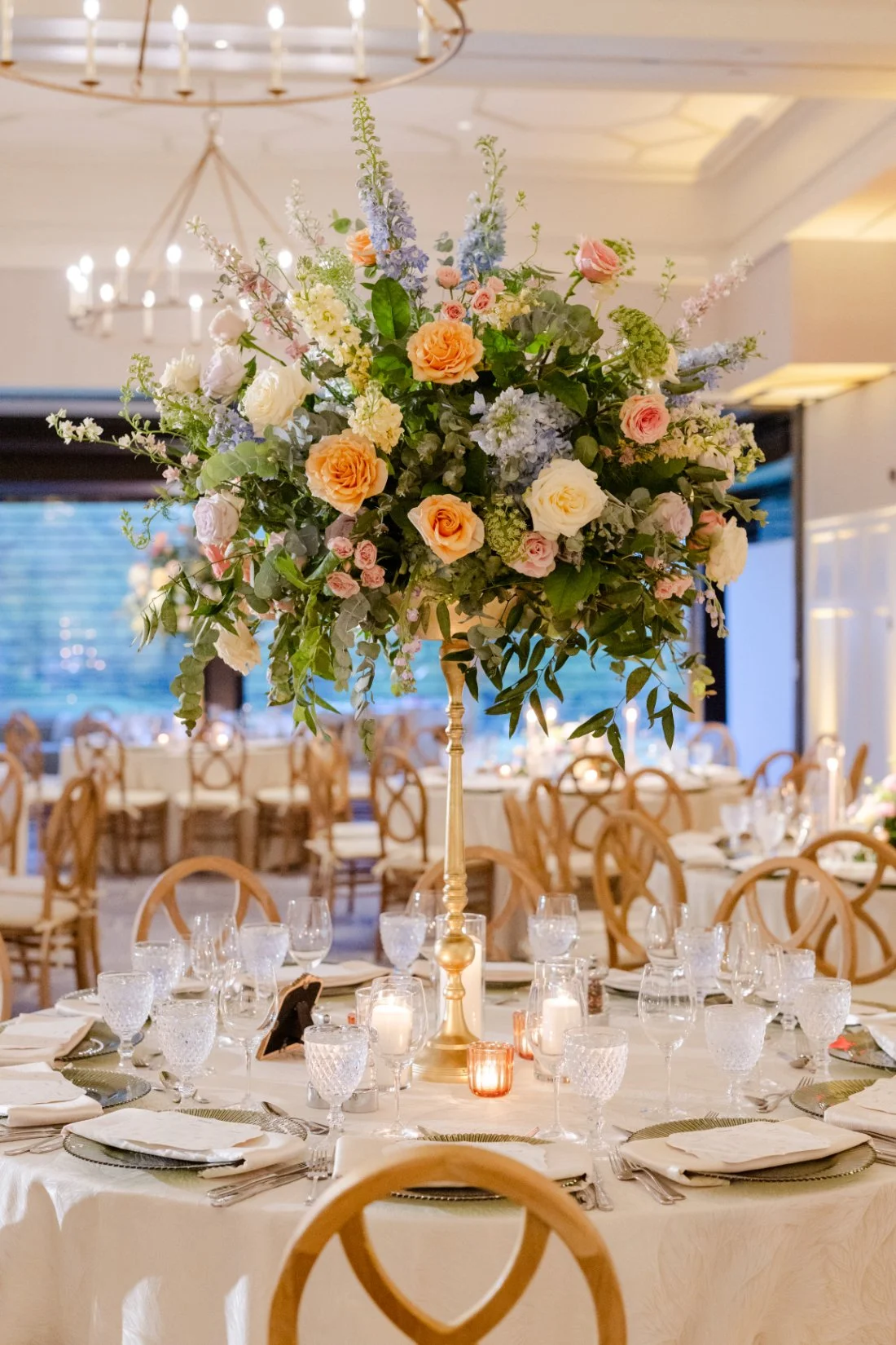 Large colorful floral centerpiece decorating a round table at a Quaker Ridge Golf Club wedding reception.