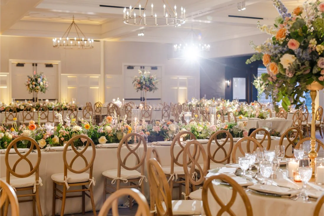 Elegant wedding reception space filled with florals and beautifully set tables.