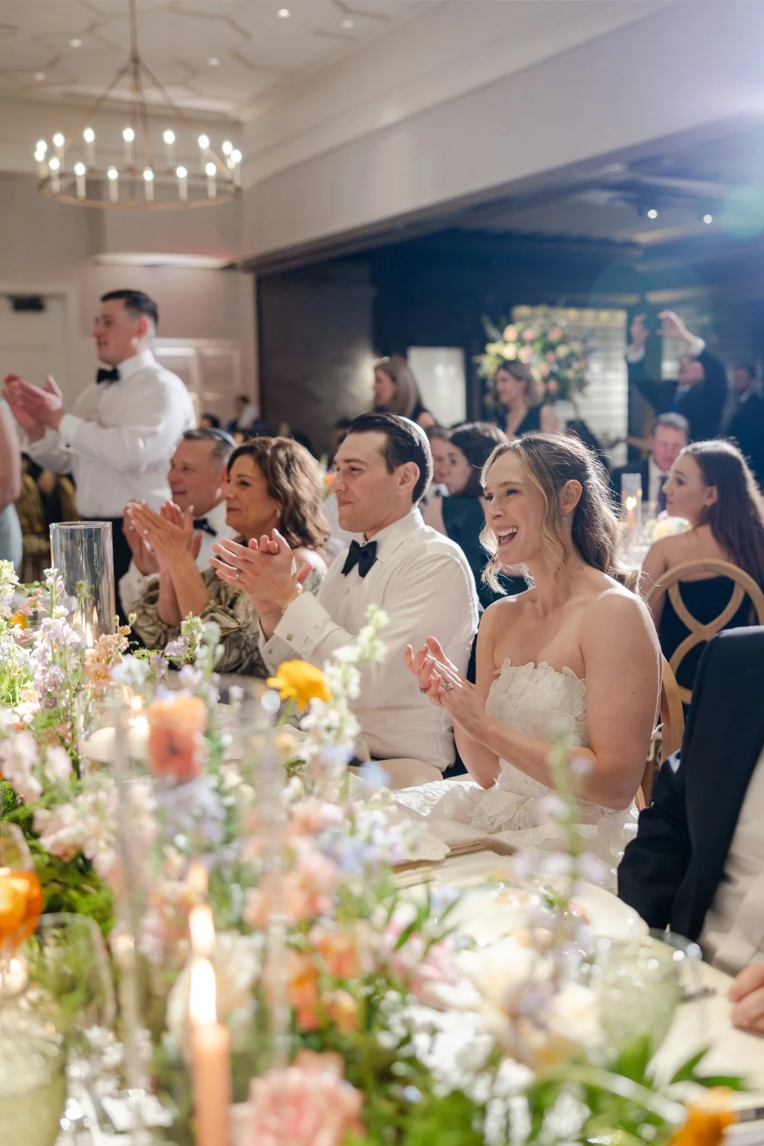 Wedding guests smiling and reacting during the reception speeches.