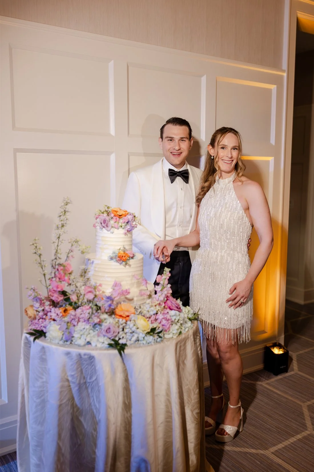 Bride and groom cutting their colorful wedding cake together.