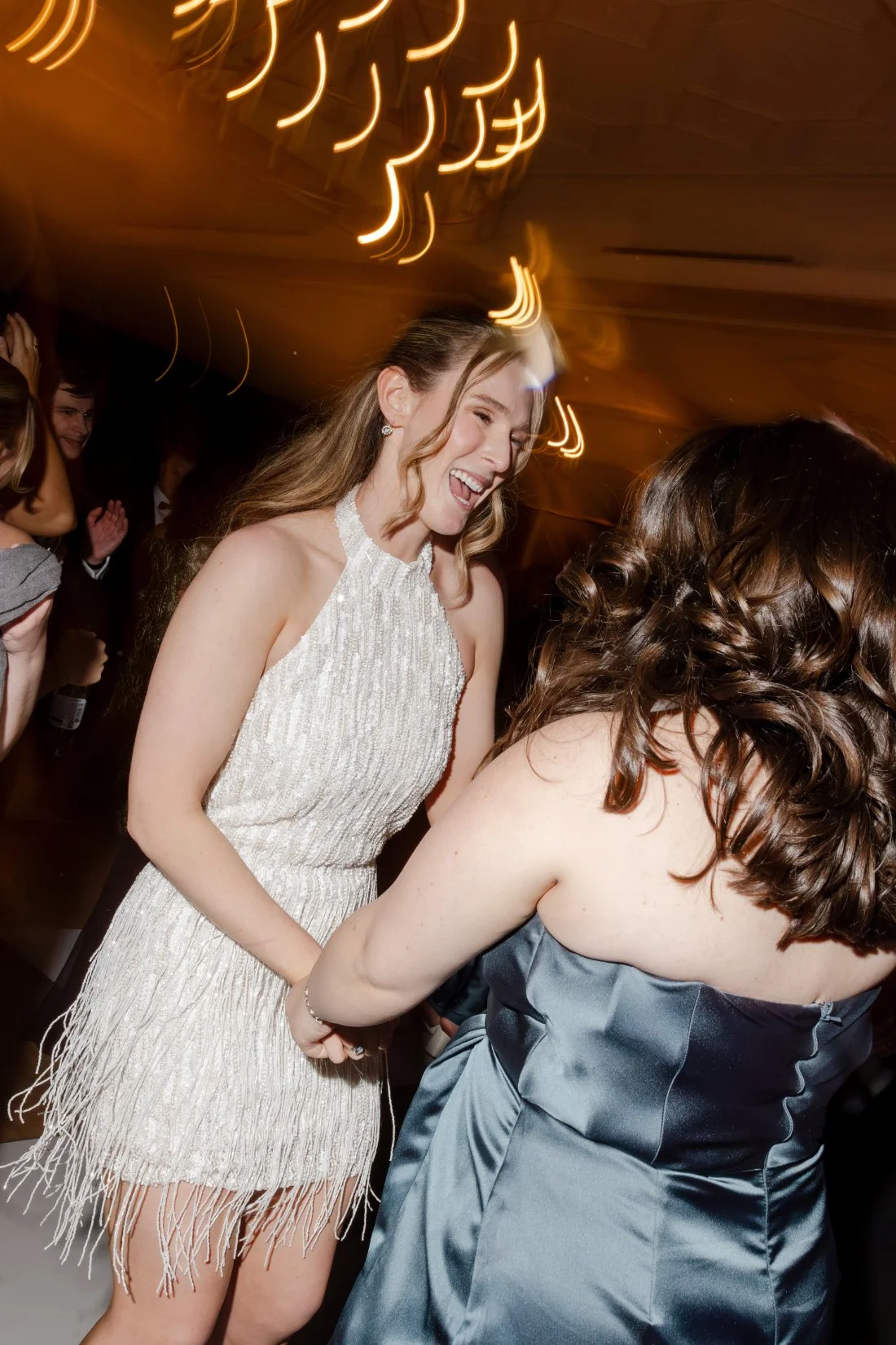 Bride chatting with a guest while wearing her sparkling white reception dress.
