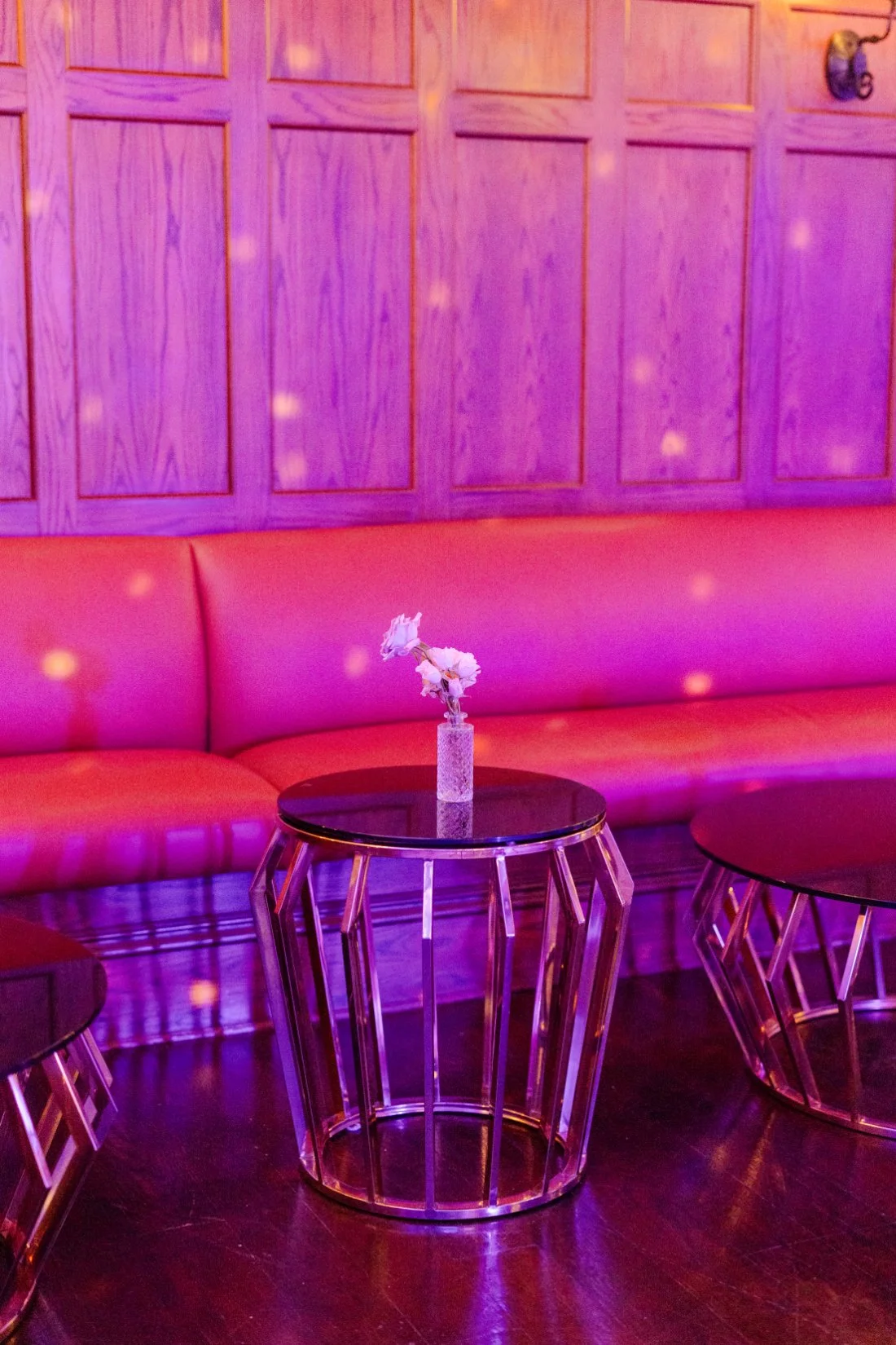 Cocktail table and lounge seating illuminated by colorful lights at the Quaker Ridge Golf Club wedding.