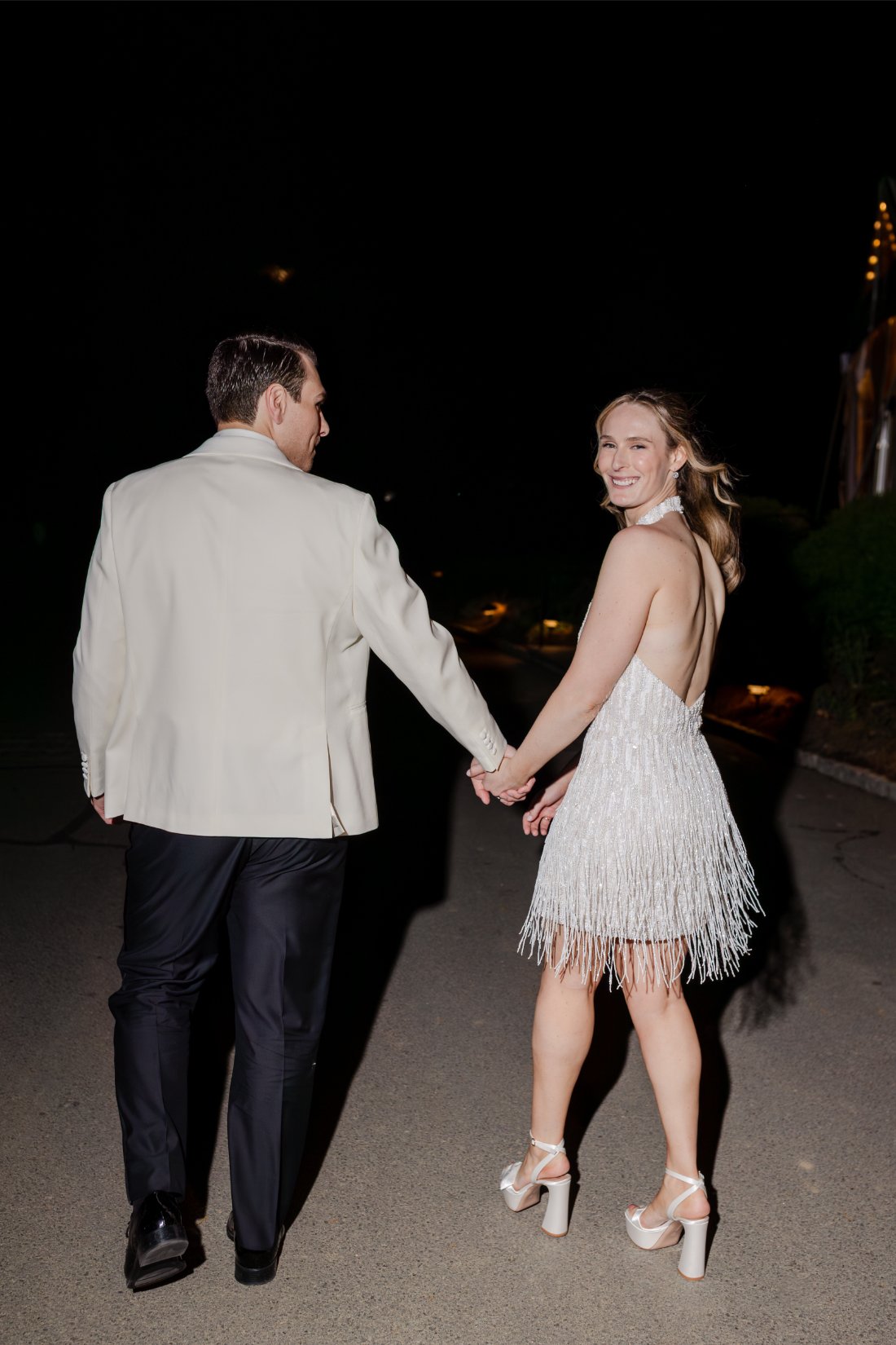 Bride and groom holding hands during a nighttime wedding portrait.