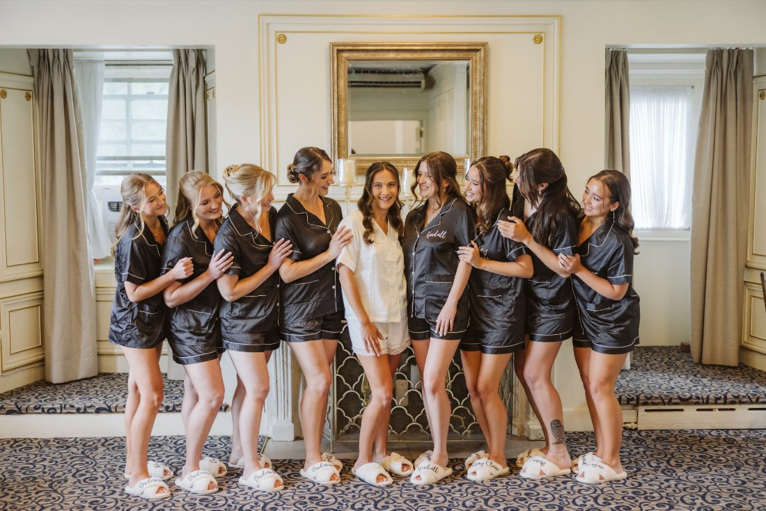 Bride and bridesmaids wearing matching pajamas and slippers while getting ready together on the wedding morning.
