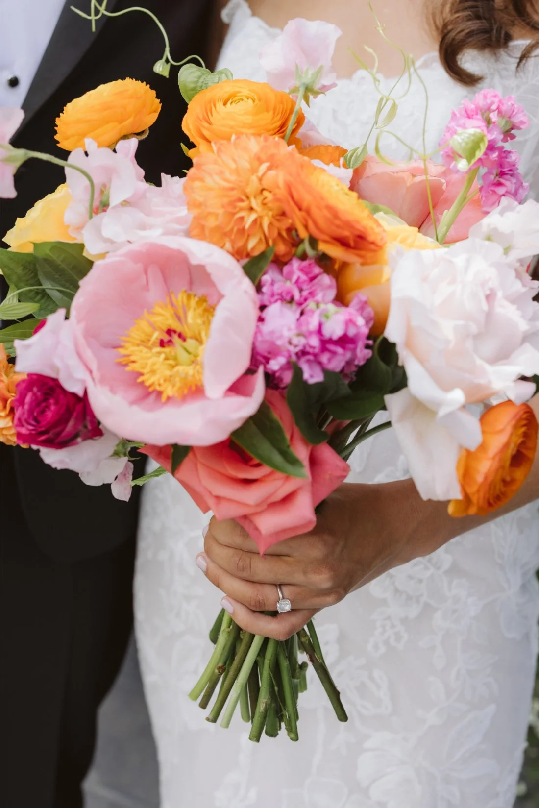 Close-up of Sydney’s vibrant bridal bouquet featuring pink peonies, orange ranunculus, and coral roses at her Tappan Hill Mansion wedding.